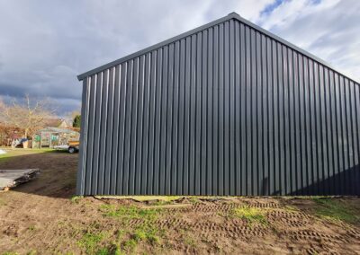 In een veld wordt een zwart metalen gebouw gebouwd.
