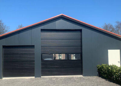 Een zwarte garage met een rode deur.