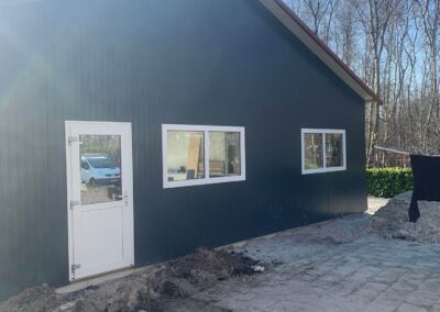 Een gebouw in aanbouw met een zwarte deur en ramen.