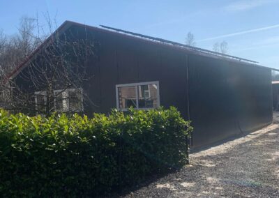 Een bruin gebouw met struiken ervoor.