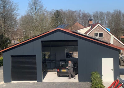 Een garage met een auto ervoor geparkeerd.