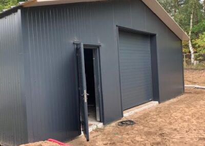 Een garage met een zwarte deur en een vuilvloer.