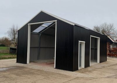 Een zwart metalen gebouw met een wit dak.