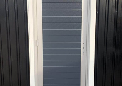 Een garagedeur met een zwart frame en een grijze deur.