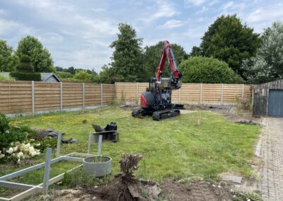 In een achtertuin wordt een graafmachine ingezet voor een Projectpagina Hoboken (B) project.