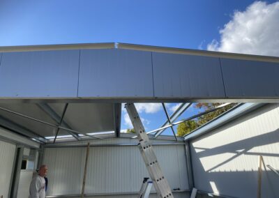 Een man staat op een ladder in een metalen gebouw uit Hoboken (B).
