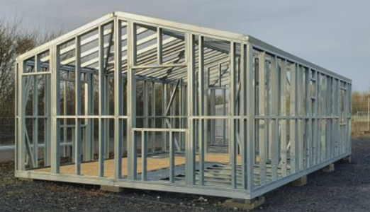 In een veld wordt een gebouw met een metalen frame gebouwd.